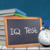 Word IQ TEST against red apple on pile of books in classroom
